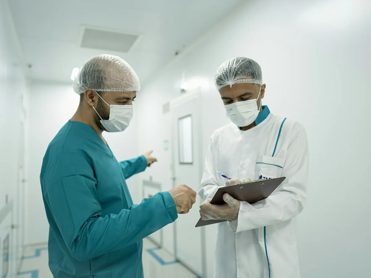 Dos especialistas con uniforme quirúrgico revisan una lista en un pasillo de hospital
